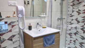 Une salle de bain moderne avec une douche à l’italienne en verre, un lavabo blanc avec un meuble-vasque en bois et un miroir au-dessus du lavabo.