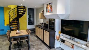 Eine moderne Küche mit Einbauofen, einem großen Flachbildfernseher und einem Holzesstzimmer mit Stühlen.