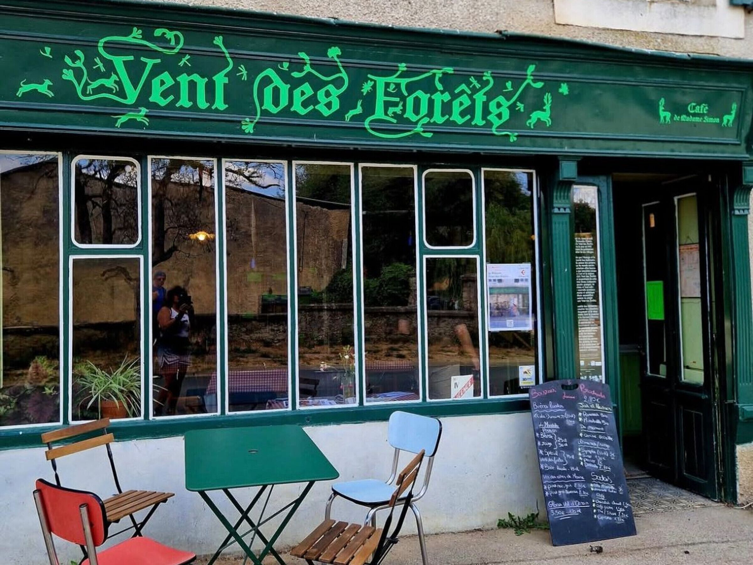A cafe with a green awning and a chalkboard menu outside.