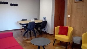 A conference room with a wooden table, black chairs, a small table, and a red couch. - Duplex 2BR for 5 - Ski-In/Ski-Out, Garage, Free Shuttle (Les Gets)