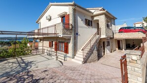 Un edificio di due piani con un balcone, una scala e un'auto parcheggiata davanti.