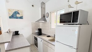 A compact kitchen with white cabinetry, a microwave, a dishwasher, and a stove. - Elegant modern villa steps from the beach (Biscarrosse Plage)