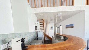 Una cocina moderna con encimera de madera, una cafetera y vistas al piso superior.