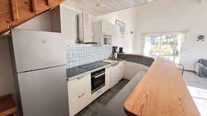 A compact kitchen with white cabinets, a black countertop, and a wooden table. - Spacious Villa Near Beach, 8 People (Biscarrosse Plage)