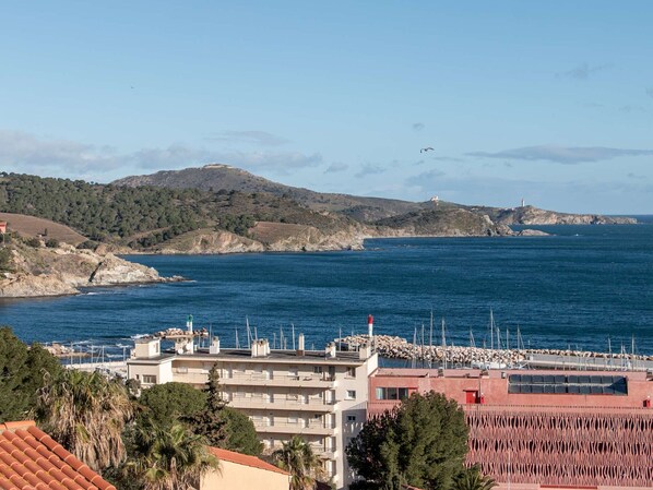 Vista costera con edificios, un faro y un puerto deportivo.