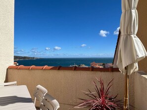 A balcony with a view of the sea, a white umbrella, and a chair. - Modern duplex 3 bed - 6 pers, parking, near port (Banyuls-sur-Mer)