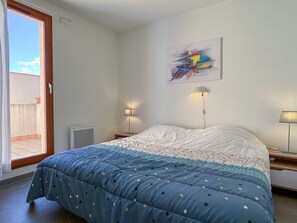 Un dormitorio con una cama, una ventana, una puerta y una obra de arte colgada en la pared.