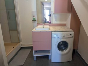 Un baño pequeño con lavamanos, espejo y lavadora.