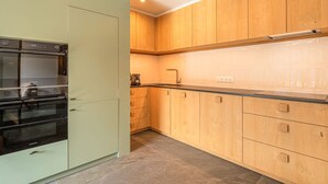 Eine moderne Küche mit eingebautem Backofen, Holzschränken und einer gefliesten Spritzschutzwand.