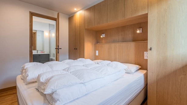 Ein Schlafzimmer mit einem großen Bett, einem Holzschrank und einem Spiegel.
