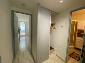 Un corridoio con una porta scorrevole che dà su una stanza con il bagno e uno scaffale con un oggetto appeso.