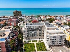 A high-rise residential building with multiple balconies, a central courtyard, and a view of the sea.