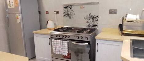 A kitchen with a stainless steel stove, a refrigerator, and white cabinetry.