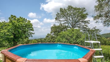 Ein rechteckiger Pool mit Holzrand, umgeben von üppiger Vegetation und Bäumen.
