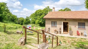 A rustic house with a tiled roof, a wooden staircase, and a garden with outdoor furniture. - Tenuta Focaioni - Monte Amiata (Stribugliano)