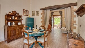 A dining area with a round table, chairs, and a wooden cabinet. There is a door leading to an outdoor area. - Tenuta Focaioni - Monte Amiata (Stribugliano)