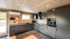 Une cuisine moderne avec un lambris en bois, un four encastré et une grande fenêtre.