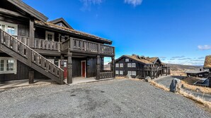 A rustic wooden building with a balcony and a staircase leading to the entrance.