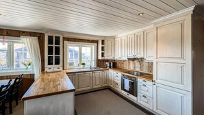 A kitchen with wooden cabinets, a wooden countertop, and a window with a view.