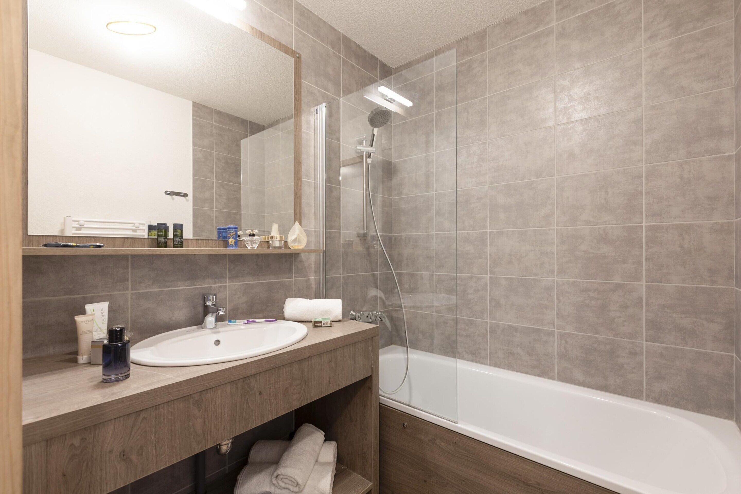 A modern bathroom with a sink, mirror, and shower.