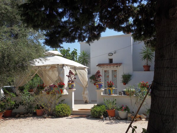 A courtyard with a white building, potted plants, and a canopy. - Romantic Puglian Hideaway for couples with Panoramic Sea Views (Carovigno)