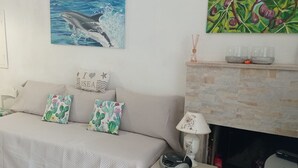 A bedroom with a bed, pillows, a painting of a dolphin, a fireplace, and a staircase. - Romantic Trullo for 2  sea view pool,peaceful garden rustic  authentic Puglia (Carovigno)