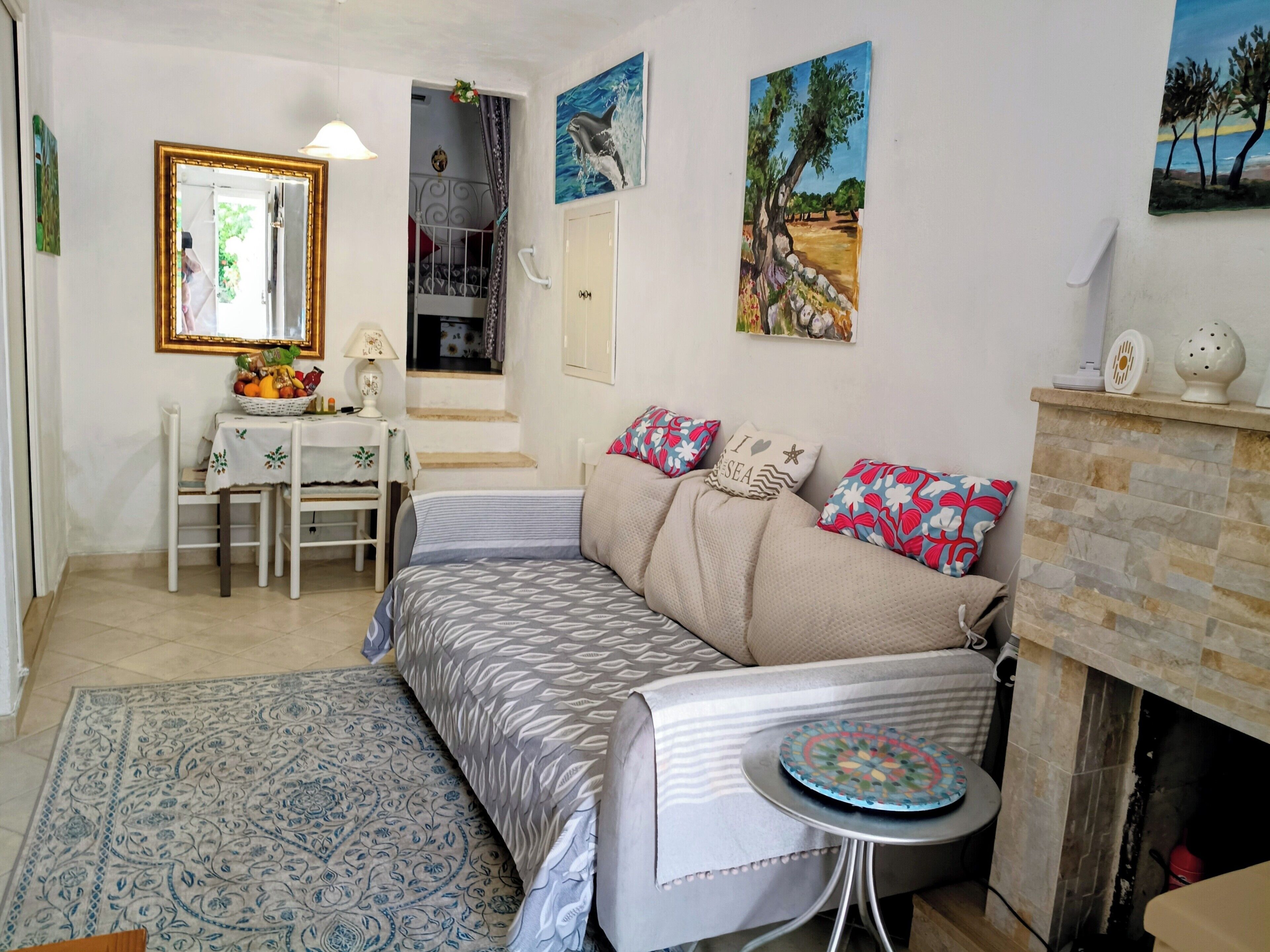 Una sala de estar con sofá, una pequeña mesa redonda, chimenea y una escalera que sube a un nivel superior.