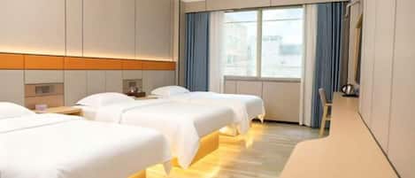 A hotel room with three beds, a large window with curtains, and a wooden floor.