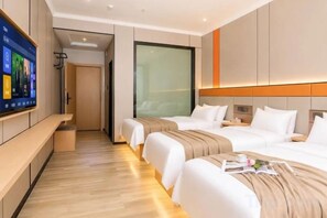 Habitación de hotel con dos camas, un televisor en la pared y piso de madera.