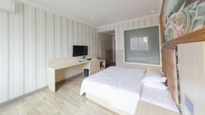 Una habitación de hotel moderna con una cama grande, un escritorio y un televisor de pantalla plana, además de un ventanal amplio.