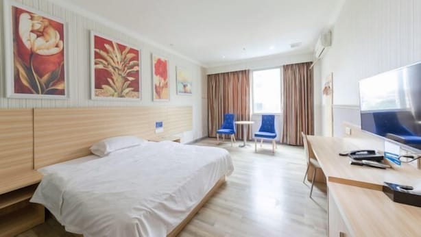 Una habitación de hotel con cama, escritorio, televisión y obras de arte en las paredes.