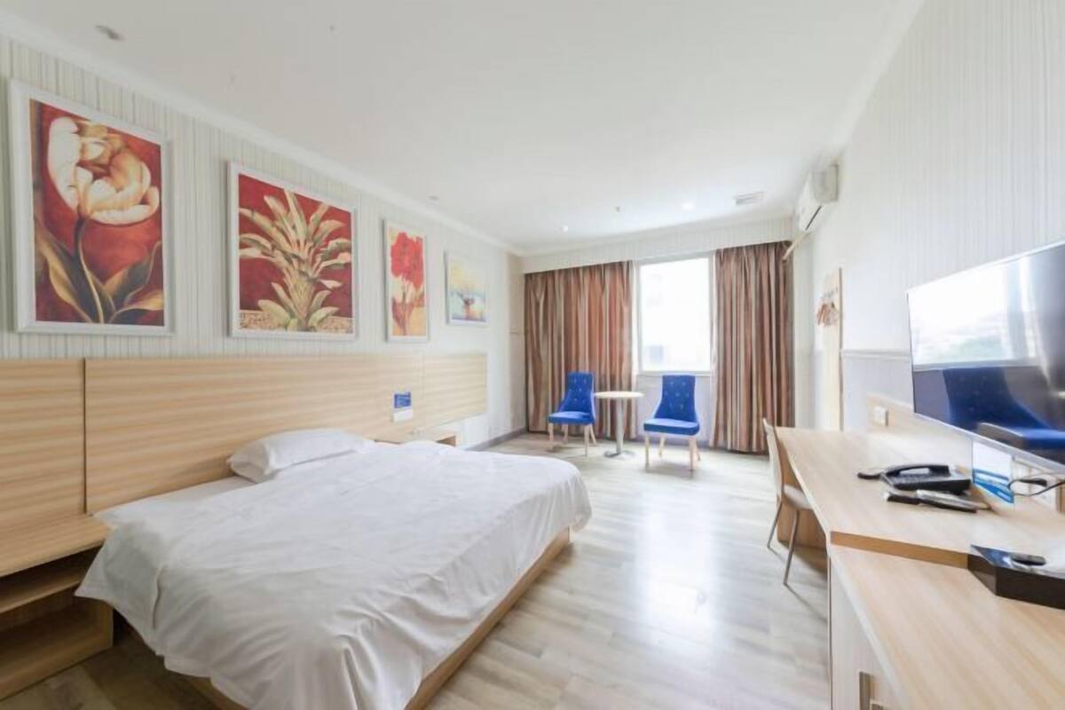 Une chambre d’hôtel équipée d’un lit, d’un bureau, d’une télévision et décorée avec des œuvres d’art.