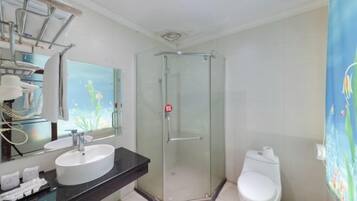 Een badkamer met een douchecabine, een wit wastafeltje en een toilet.