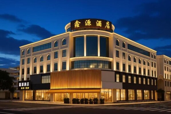 Un hotel moderno con fachada curva, amplias ventanas y una entrada destacada.