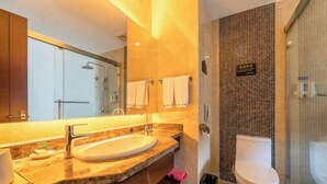 Une salle de bain moderne avec un grand miroir, un lavabo, des toilettes et un espace douche.