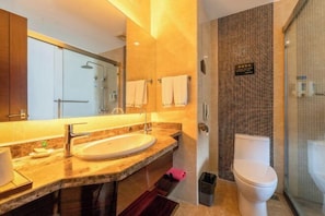 Uma casa de banho moderna com um espelho grande, uma pia, sanita e área de duche.