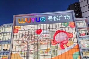 A modern building with a large glass facade, featuring a prominent sign with colorful text and graphics.