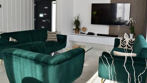 Una sala de estar moderna con sofás verdes, un televisor de pantalla plana y un diseño minimalista.