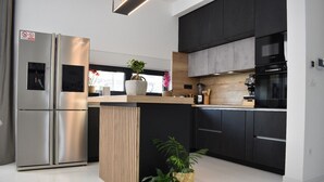 Una cocina moderna con un refrigerador de acero inoxidable, una isla de madera y armarios negros.