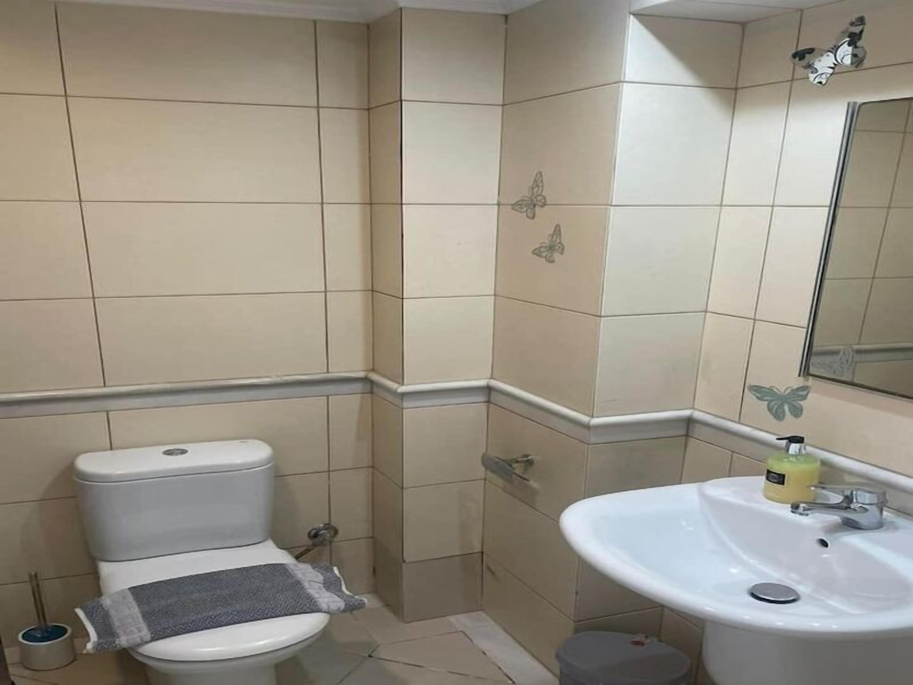 A bathroom with a toilet, sink, and tiled walls.