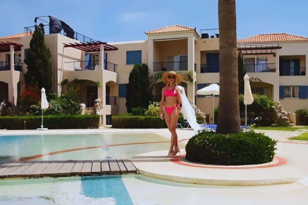 A pool area with a clear water surface, surrounded by a poolside deck and lounge chairs.
