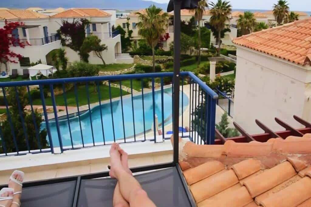 Un balcone con vista sulla piscina, un tetto in tegole e una ringhiera.