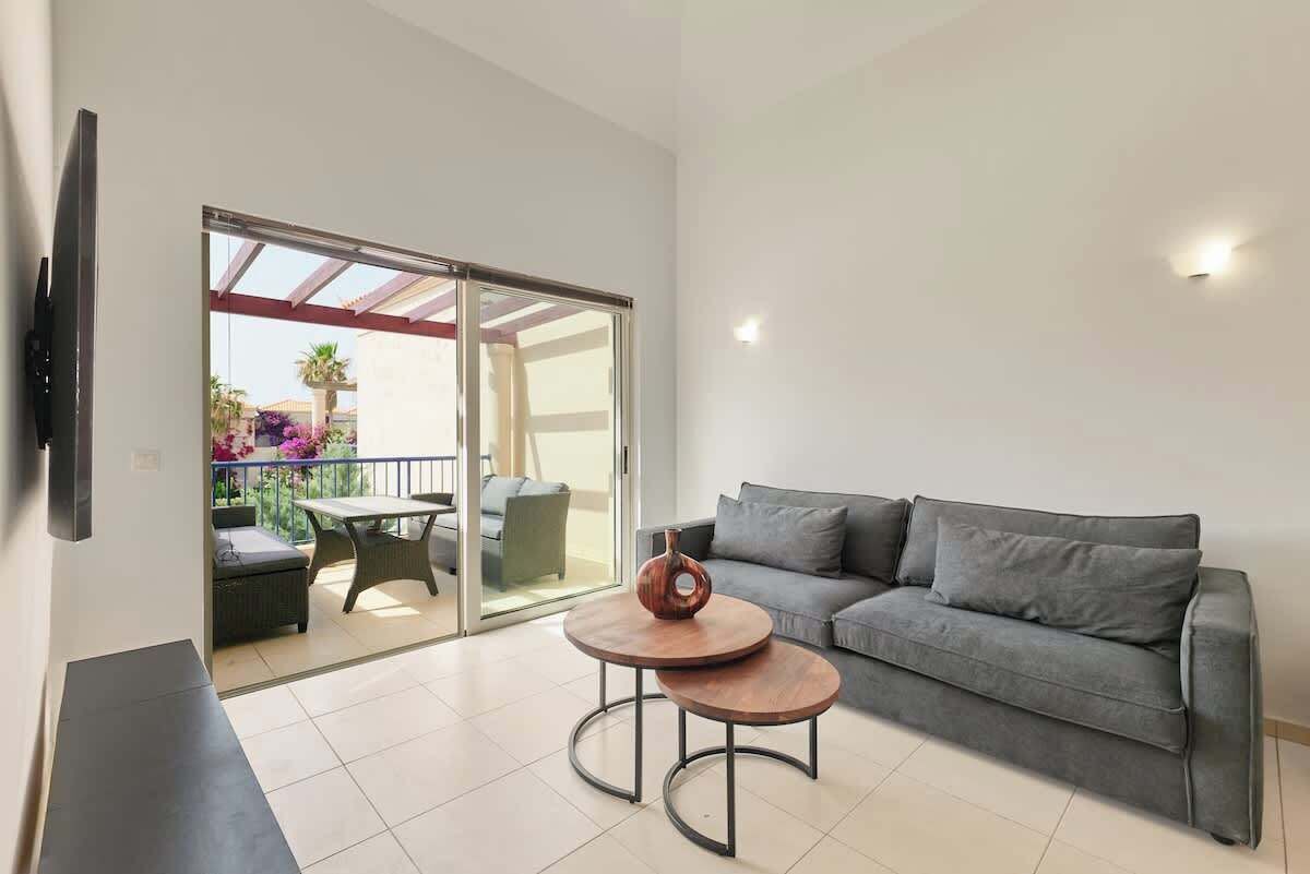 A modern living room with a grey sofa, a round coffee table, and a TV mounted on the wall.