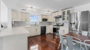 Una cocina moderna con gabinetes blancos, electrodomésticos de acero inoxidable y una mesa de comedor de madera.