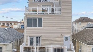 Un edificio de dos pisos con un balcón en el nivel superior y una terraza techada.