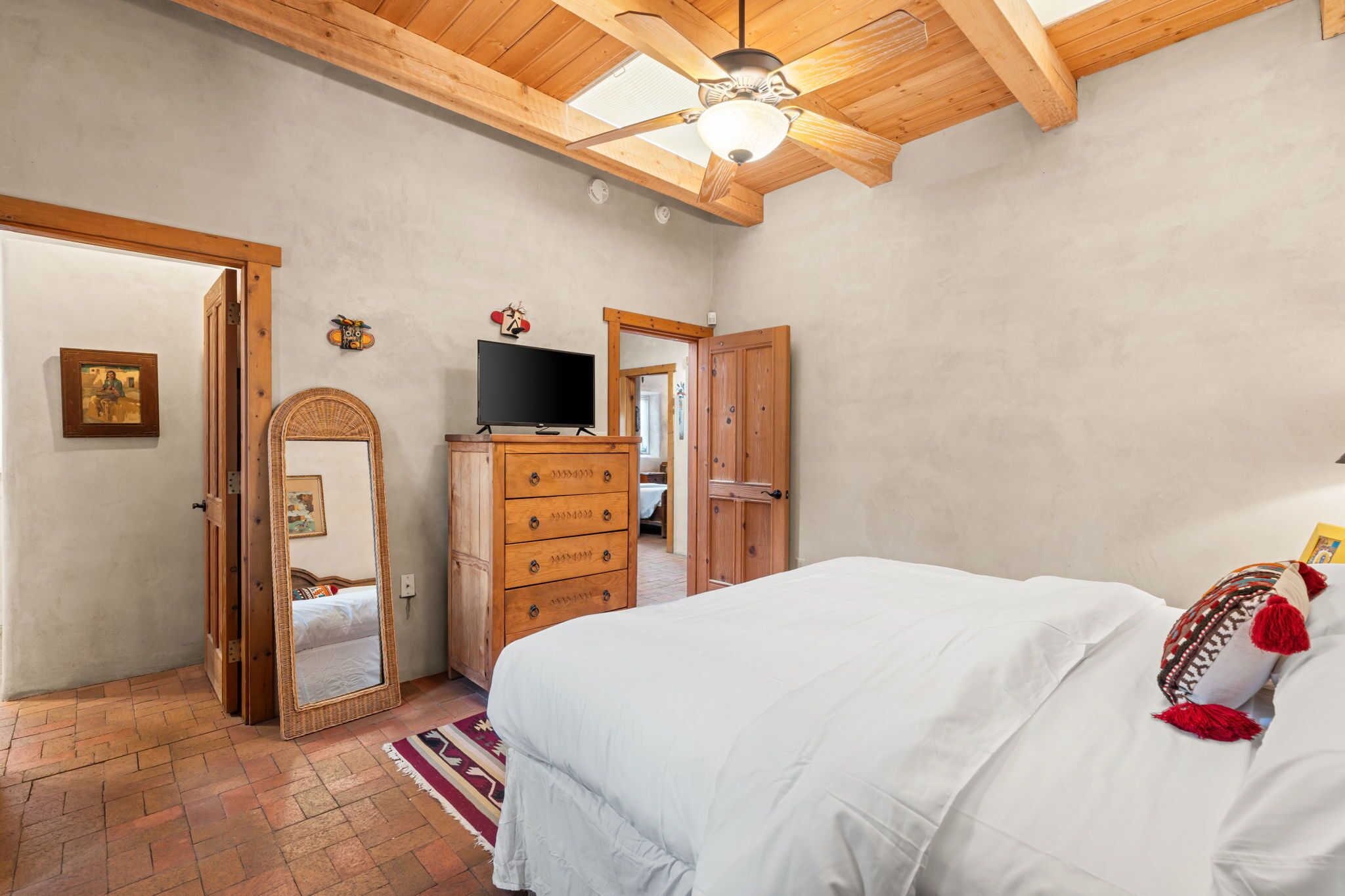 Ein Schlafzimmer mit Bett, einem Holzschrank, Fernseher und Deckenventilator.