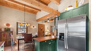 Una cocina con un refrigerador de acero inoxidable, vigas de techo de madera y un armario verde.