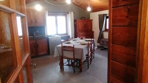 A wooden interior with a dining table set for four, a kitchen area, and a large cabinet. - Maisonnette 4/5 persons in Saint-Véran 2*. (Saint-Véran)