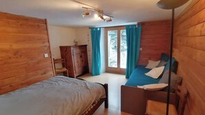 A wooden cabin room with a bed, a desk, a chair, and a window with curtains. - Maisonnette 4/5 persons in Saint-Véran 2*. (Saint-Véran)