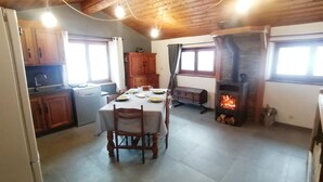 A cozy kitchen with wooden cabinets, a dining table set for four, and a wood-burning stove. - Maisonnette 4/5 persons in Saint-Véran 2*. (Saint-Véran)